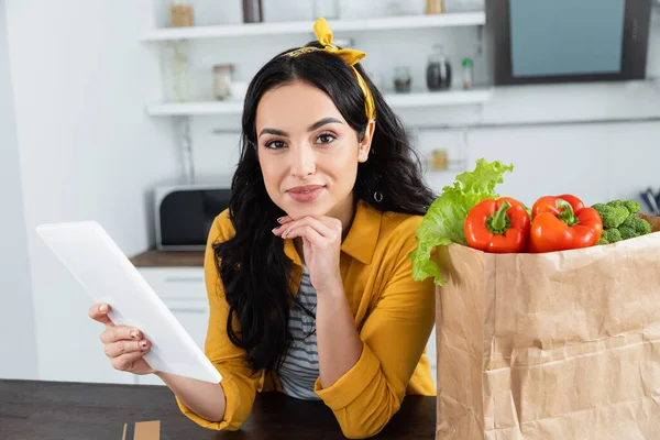 Glad Brunett Kvinna Med Hjälp Digital Tablett Nära Papperspåse Med — Stockfoto