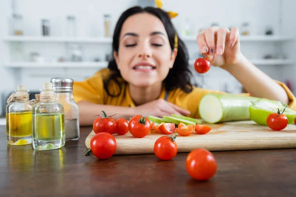 Mujer Joven Borrosa Sosteniendo Tomate Cereza Maduro Cerca Verduras Tabla — Foto de Stock