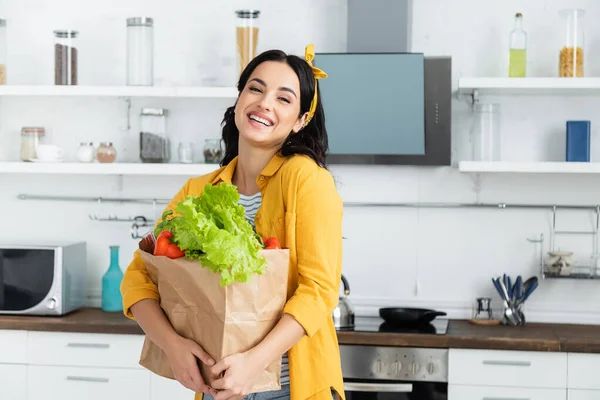 幸せなブルネット女性保持紙袋で熟した野菜 — ストック写真