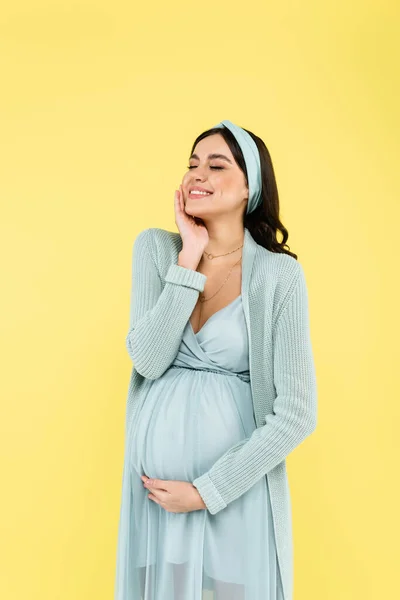 Potěšená Těhotná Žena Dotýkající Obličeje Zatímco Stojí Zavřenýma Očima Izolované — Stock fotografie
