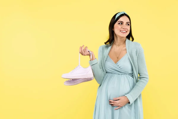 Nöjd Gravid Kvinna Röra Magen Medan Hålla Sneakers Isolerade Gul — Stockfoto