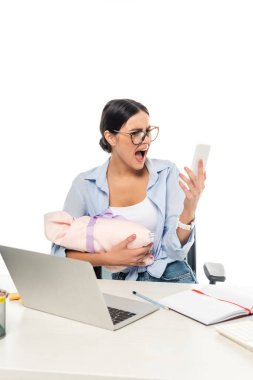 Sinirli iş kadını, iş yerinde elinde akıllı telefon ve bebekle çığlık atıyor.