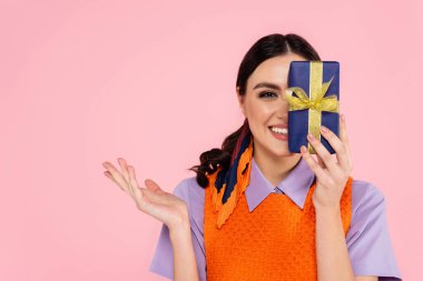 Neşeli kadın yüzünü pembe bir hediye kutusuyla kapatıyor.