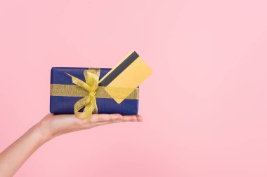 Hediye kutusu ve pembe üzerine izole edilmiş kredi kartıyla kadın eli görüntüsü.
