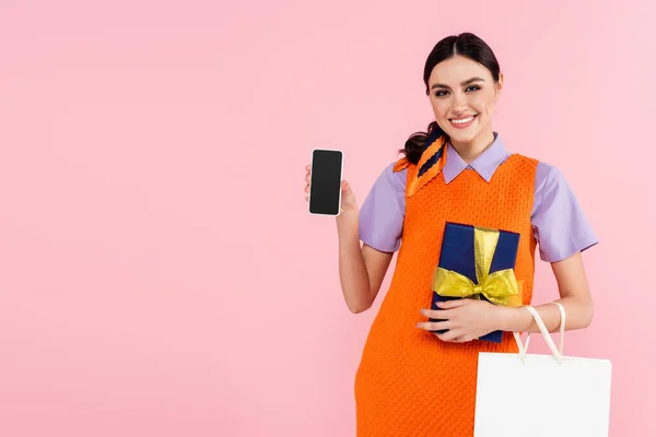 Happy Woman Showing Mobile Phone Blank Screen While Holding Presents — Stock Photo, Image