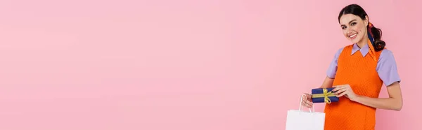 Jonge Vrouw Met Boodschappentas Geschenkdoos Glimlachen Camera Geïsoleerd Roze Banner — Stockfoto