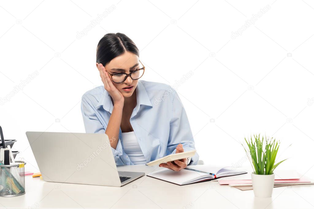 thoughtful businesswoman working with calculator near laptop isolated on white