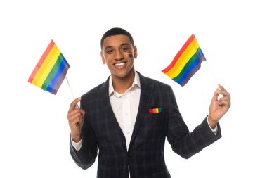Afro-Amerikan transseksüel kadın lgbt bayrakları tutarken kameraya gülümsüyor.