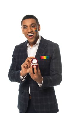 Heyecanlı Afrikalı Amerikalı adam yüzünde lgbt bayrağı ile beyaza izole edilmiş alyansı gösteriyor.
