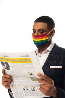 Afro-Amerikan homoseksüel iş adamı LGBT renklerinde koruyucu maske okuyarak beyazlara izole edilmiş haberleri okuyor.