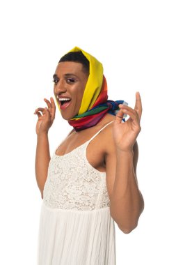 Heyecanlı Afro-Amerikan transseksüel adam. Elbise ve gökkuşağı renginde. Başörtüsü beyaz tenli.