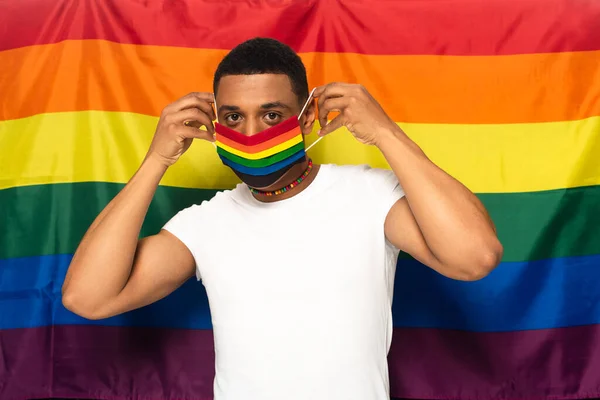 年轻的非洲裔美国人戴着彩虹色的防护面具 背景是Lgbt旗 — 图库照片