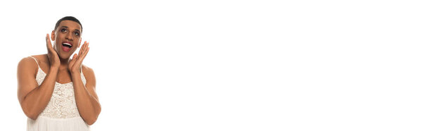 astonished african american transgender man holding hands near face while looking up isolated on white, banner