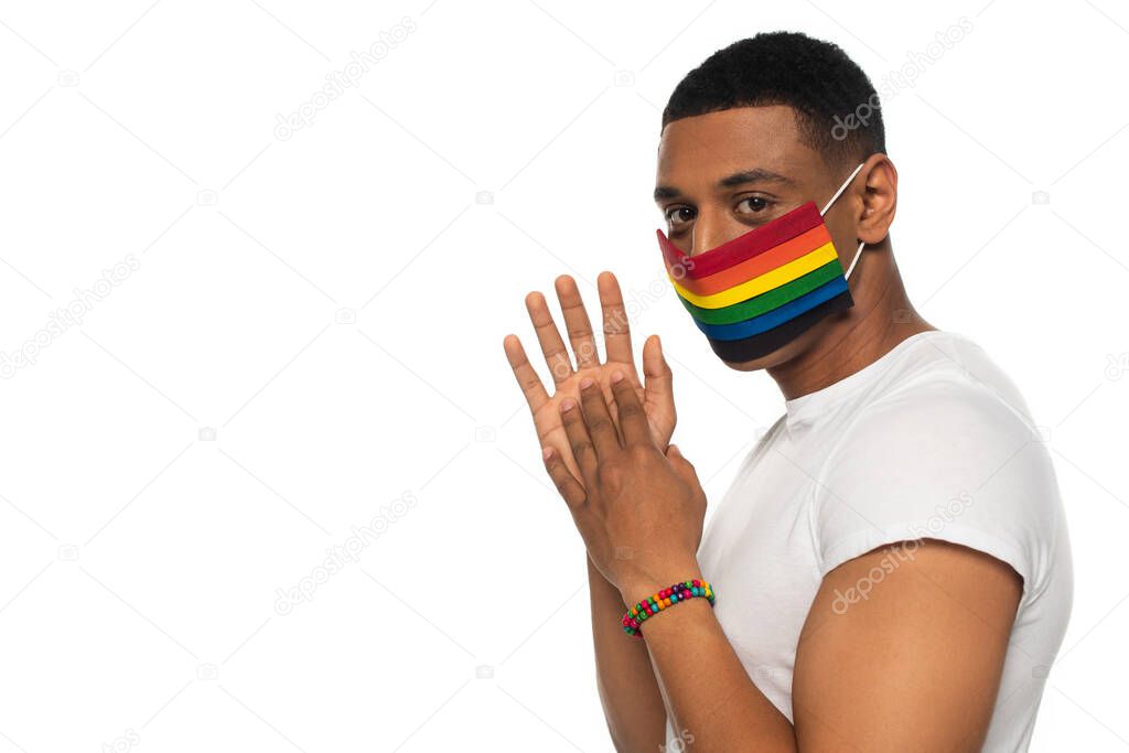 african american man in medical mask and beads bracelet in lgbt colors looking at camera isolated on white