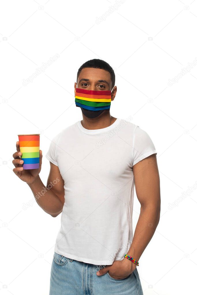 african american man with lgbt colors paper cup and protective mask standing with hand in pocket isolated on white