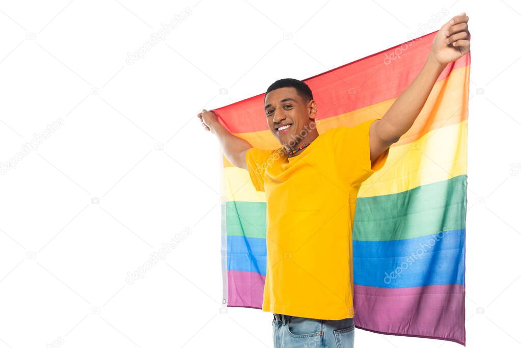 pleased african american man smiling at camera while holding lgbt flag isolated on white