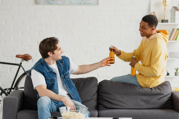正の異人種間の友人がリビングルームでビールを飲み — ストック写真