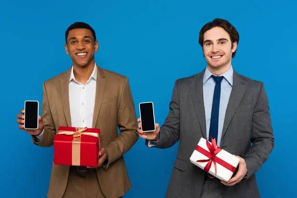Smiling Young Interracial Men Fashionable Suits Holding Gift Boxes Showing — Stock Photo, Image