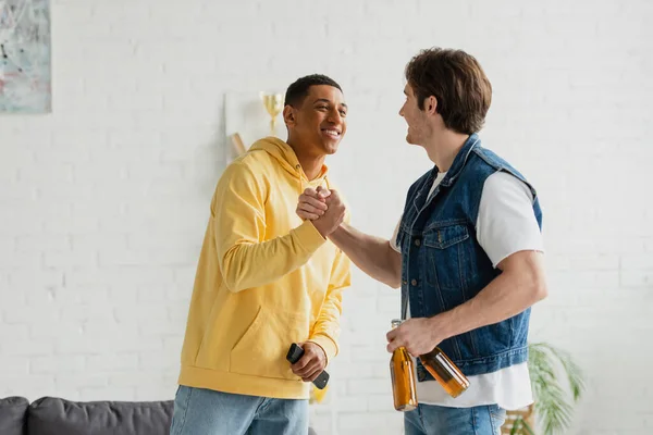 Glückliche Interrassische Freunde Die Sich Hause Mit Händeschütteln Und Bier — Stockfoto