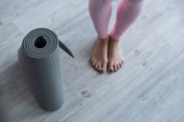 Çıplak ayaklı kadının yanındaki yoga minderinin seçici odak noktası.