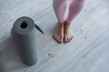 selective focus of yoga mat near barefoot woman, cropped view clipart