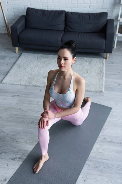 在瑜伽垫上高角镜下 赤脚女子在膝盖上练习凸起姿势 — 图库照片