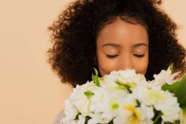 Afro-Amerikan reşit olmamış kız bej rengi gözlerle kapalı papatya buketi kokluyor.