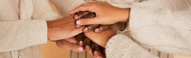 close up shot of african american middle aged, adult and preteen female hands holding together on beige background, banner clipart