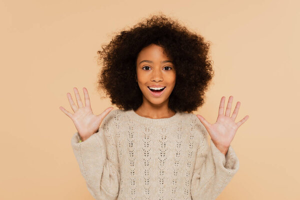 excited african american preteen girl with hands up showing palms isolated on beige
