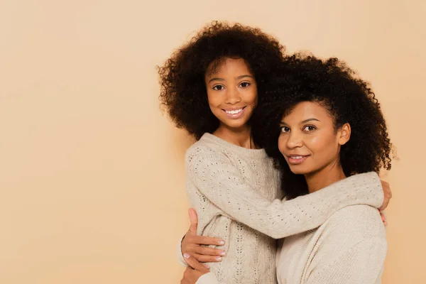 非洲裔美国人十几岁前的女儿和成年母亲在米黄色的基础上相互拥抱和微笑 — 图库照片