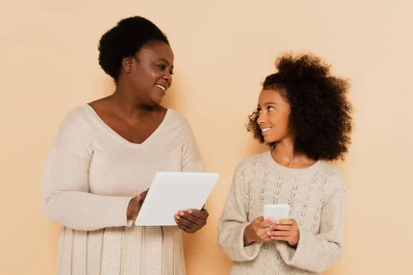 Afrikanska Amerikanska Barnbarn Med Mobiltelefon Tittar Mormor Med Tablett Beige — Stockfoto