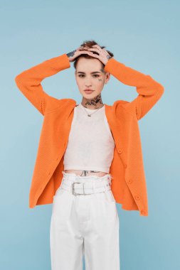 Dövmeleri olan zarif genç bir kadın. Mavi üzerinde kızıl saçlarını ayarlıyor.