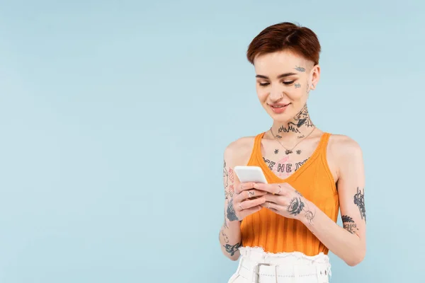 Pleased Tattooed Woman Chatting Smartphone Isolated Blue — Stock Photo, Image