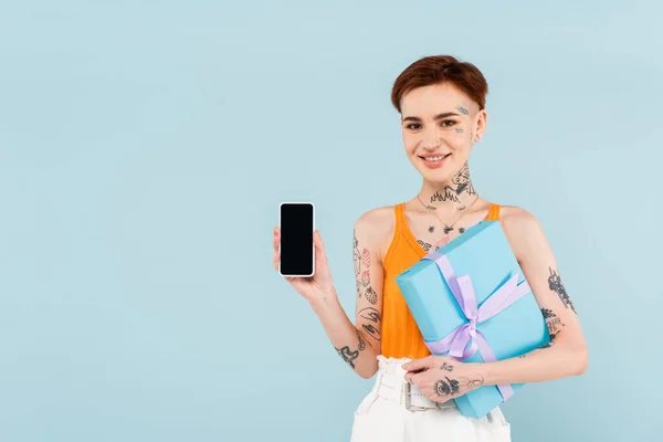 Счастливая Женщина Держит Завернутый Подарок Смартфон Чистым Экраном Изолированы Синий — стоковое фото