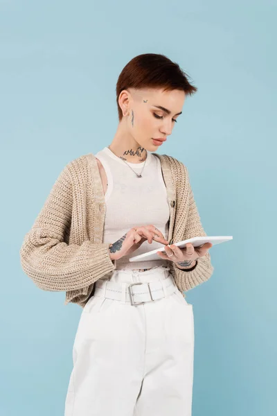 有纹身的年轻女人用数字平板隔离蓝色 — 图库照片