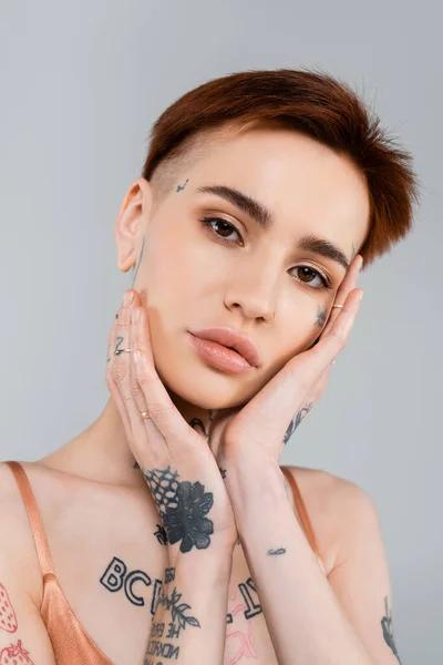 Joven Mujer Tatuada Mirando Cámara Tocando Cara Aislada Gris —  Fotos de Stock