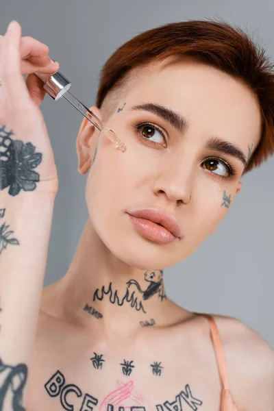 Young Tattooed Woman Applying Serum Face Pipette Isolated Grey — Stock Photo, Image