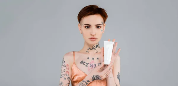 Tattooed Young Woman Holding Tube Cosmetic Product Isolated Grey Banner — Stock Photo, Image