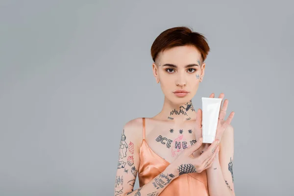 Mujer Joven Tatuada Sosteniendo Tubo Con Producto Cosmético Aislado Gris — Foto de Stock