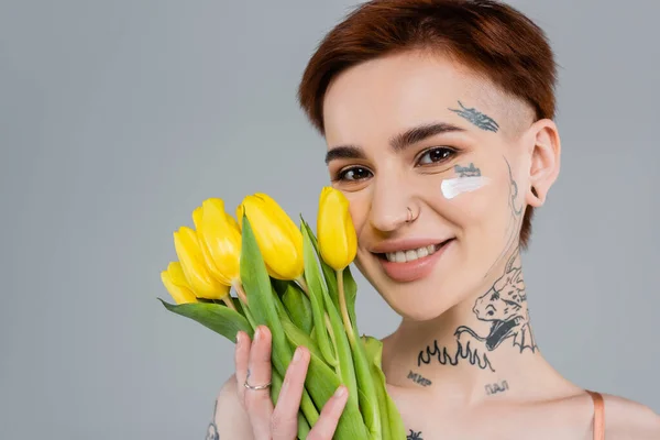 Mujer Tatuada Feliz Con Crema Cosmética Cara Sosteniendo Tulipanes Amarillos — Foto de Stock