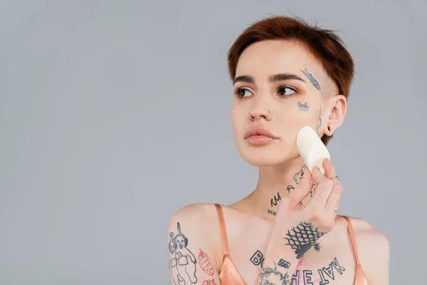 Mulher Tatuada Aplicando Base Maquiagem Rosto Com Esponja Isolada Cinza — Fotografia de Stock