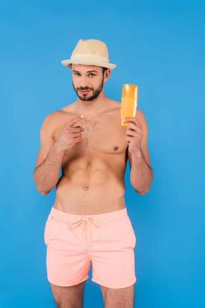 Shirless Man Met Zonnehoed Wijzend Naar Zonnebrandcrème Geïsoleerd Blauw — Stockfoto