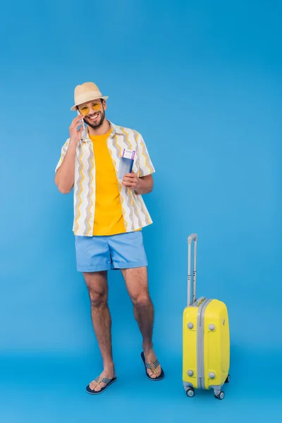 Sonriente Hombre Hablando Teléfono Inteligente Celebración Pasaporte Cerca Maleta Sobre —  Fotos de Stock