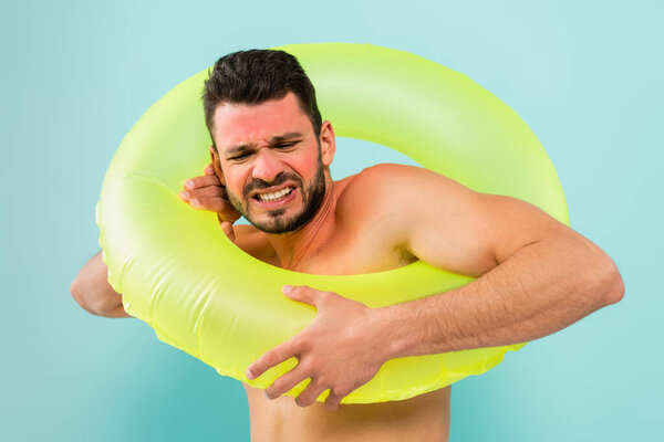 Stressed man with sunburn wearing inflatable ring isolated on blue 