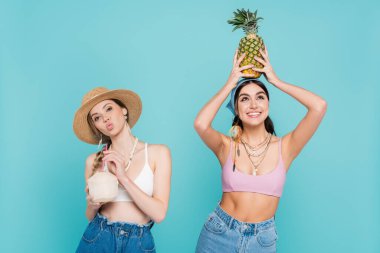 Hindistancevizli ananas ve kokteyl tutan güzel kadınlar mavi üzerine izole edilmiş. 