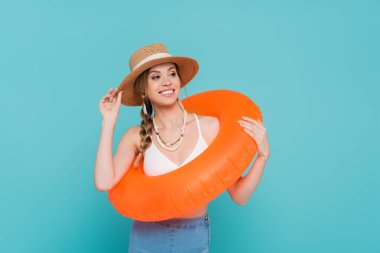 Hasır şapkalı gülümseyen kadın mavi yüzme yüzüğünü tek başına tutuyor. 