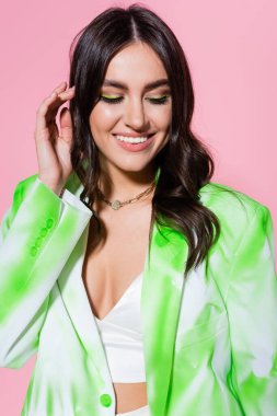 Pembe ceketli ve kolyeli gülümseyen kadın. 