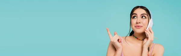 Молода Жінка Розмовляє Смартфоні Вказує Пальцем Ізольовано Синьому Банер — стокове фото