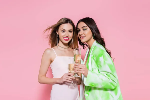 ピンクの背景にシャンパンのガラスを保持する美しい女性 — ストック写真