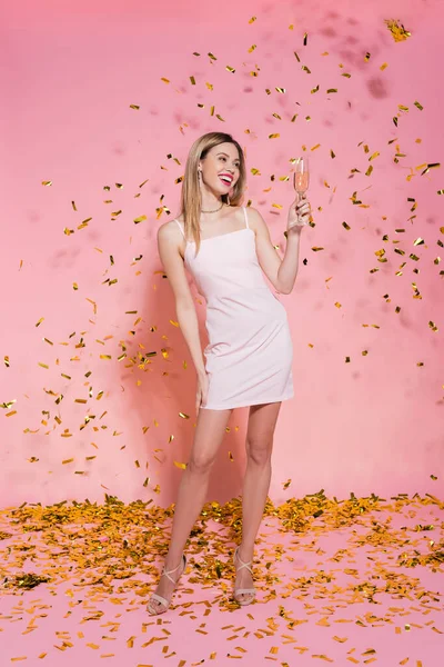 Красивая Женщина Платье Держит Шампанское Золотыми Конфетти Розовом Фоне — стоковое фото